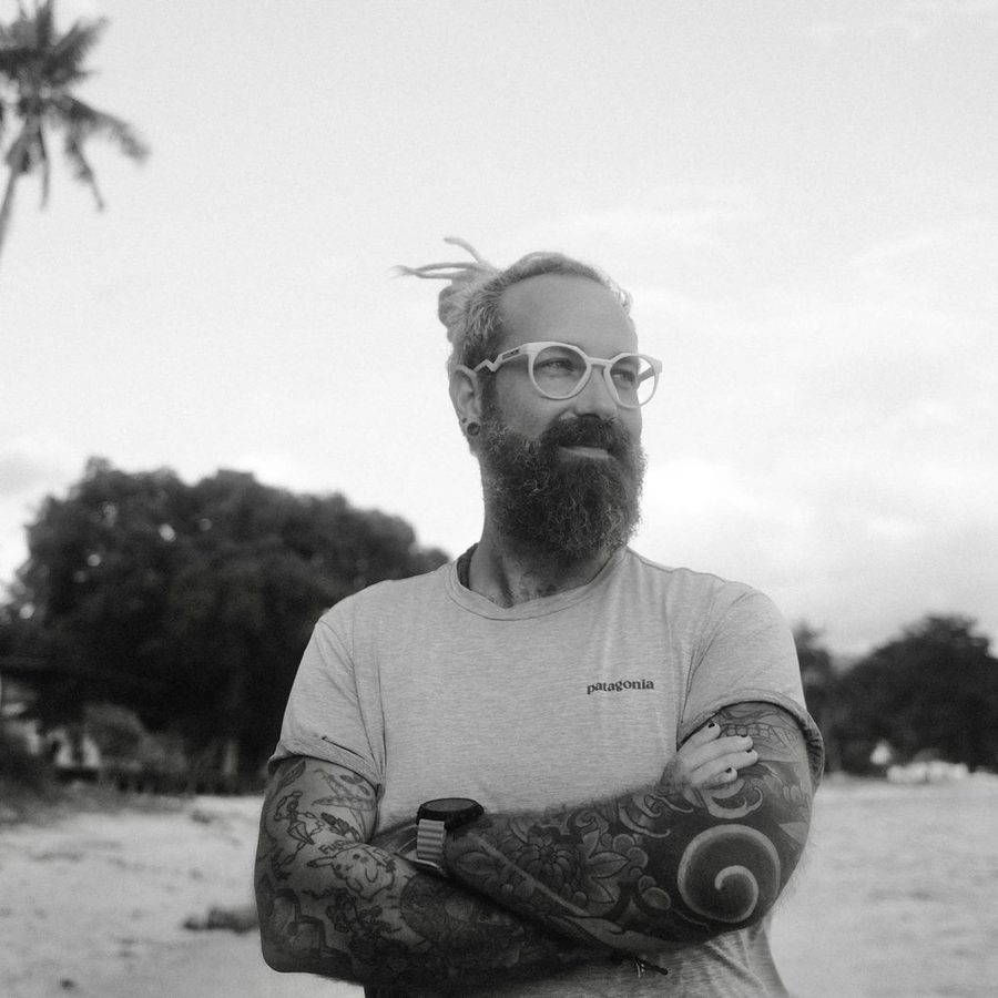 Krisztián Hadi, black-and-white portrait, arms crossed, beach behind him.